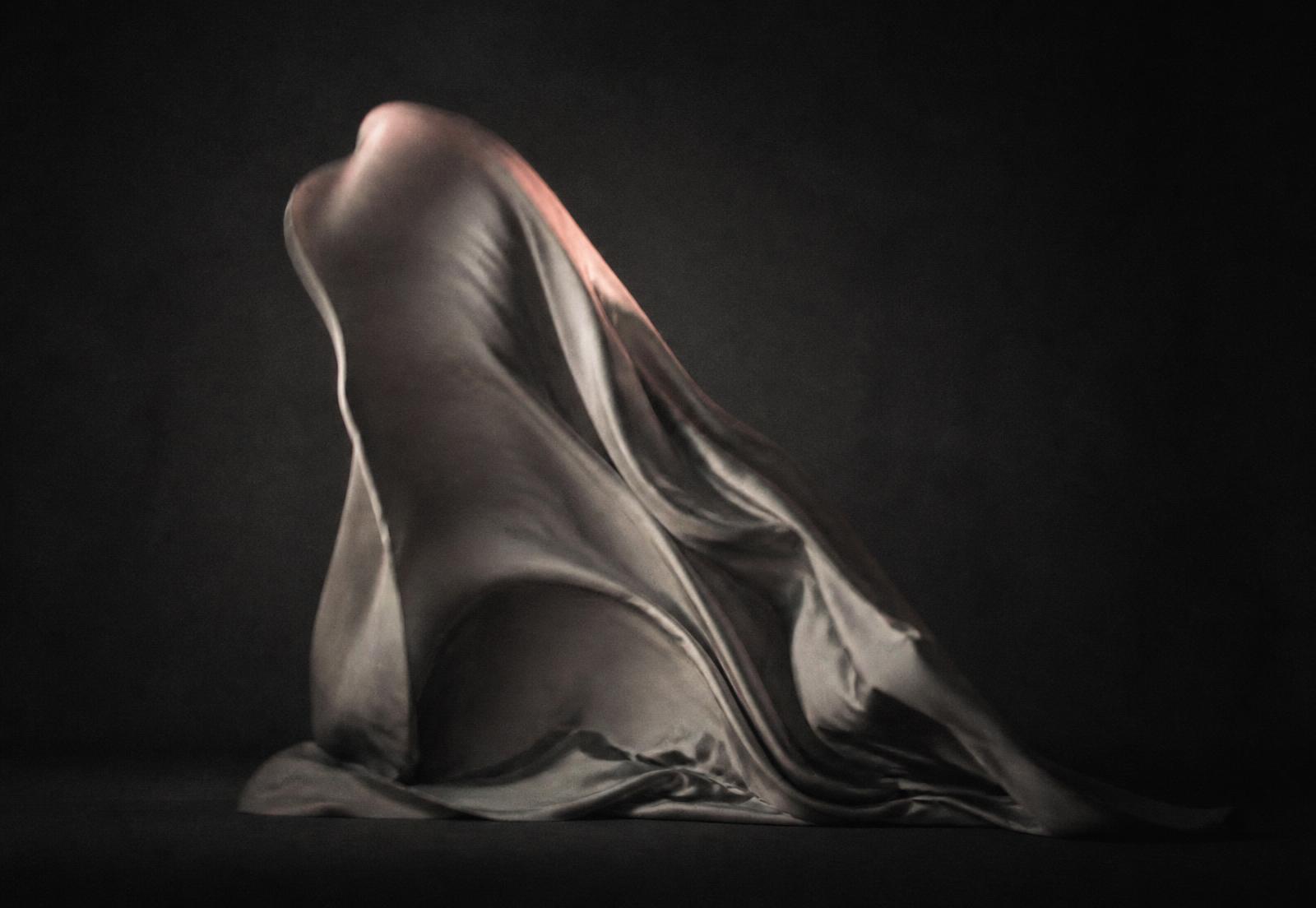 A draped form caught mid-movement under studio light